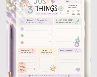 Puede incluir: Una hoja de planificador diario titulada Just 3 Things con ilustraciones en tonos pastel de un arcoíris, estrellas y corazones. El diseño incluye secciones para Today's 3 Things, If I Have Extra Energy, Don't Forget, Tiny Win y Notes & Thoughts, junto a un bolígrafo de color violeta claro.