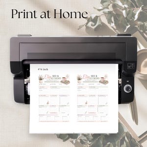 May include: A black printer outputting a white sheet of paper with two identical copies of an Etsy SEO and keyword research sheet. The document features floral graphics, a mug, and text labels. The paper is clearly marked with 4x6 inch dimensions.