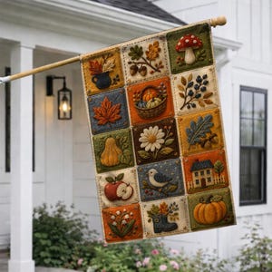 May include: A rectangular garden flag featuring a grid of twelve square panels with embroidered-style autumn motifs including a mushroom, a basket of pumpkins, a maple leaf, a bird, a house, an apple, a boot, and various seasonal foliage.