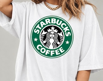May include: A white short-sleeved t-shirt featuring a large, circular green and white Starbucks Coffee logo graphic printed on the center of the chest. The design includes the iconic siren figure surrounded by the text Starbucks Coffee.