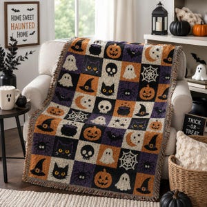 May include: A woven throw blanket featuring a repeating grid pattern of Halloween icons including orange pumpkins, black cats, white ghosts, skulls, witch hats, spiders, webs, cauldrons, and crescent moons in a colour palette of orange, purple, and black.