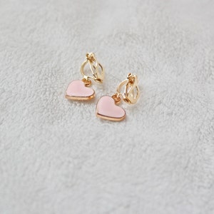 May include: A pair of gold clip-on earrings with pink heart-shaped charms.