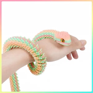 May include: A flexible, articulated snake toy featuring a pastel gradient of pink, yellow, and green scales. The snake has a textured, spiky surface and a prominent eye with a black pupil and orange iris, designed to wrap around an object.