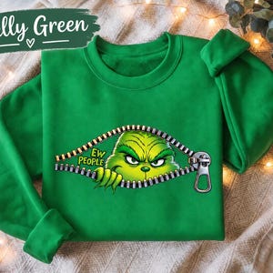 May include: A Kelly green crewneck sweatshirt featuring a graphic of a green, grumpy-looking character peeking through a metallic zipper opening. The text 'EW PEOPLE' is printed in yellow letters next to the character's face on the front of the shirt.