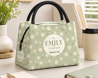 Può includere: Una borsa per il pranzo verde salvia con un motivo a margherite bianche e manici neri. La parte anteriore presenta un emblema circolare con il testo EMILY TEACHER WORKDAY FUEL. Un'etichetta circolare abbinata è fissata alla cerniera nera.