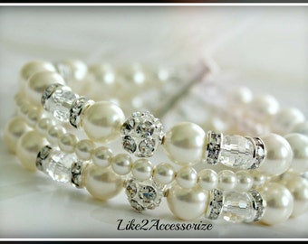 May include: Three layered pearl bracelets with crystal accents. The bracelets are white with silver accents.