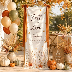 May include: A vertical banner with the text Fall in Love Sophia's BRIDAL SHOWER August 15, 2026, decorated with autumn leaves and wheat stalks. It is flanked by orange ribbons and surrounded by balloons, pumpkins, and dried floral arrangements.
