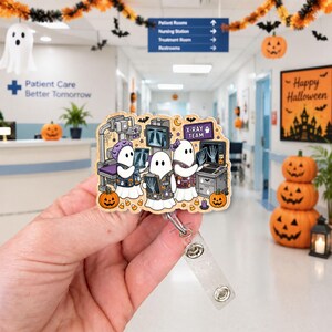 May include: A badge reel featuring a cartoon illustration of three ghosts dressed in medical scrubs, working with X-ray equipment and holding medical imaging films. The design includes pumpkins, candy corn, and a sign labeled X-RAY TEAM.