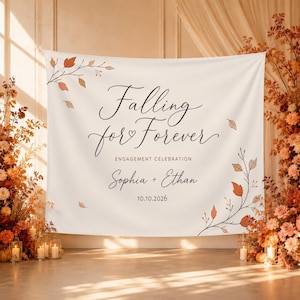 May include: A white fabric backdrop featuring the black script text Falling for Forever, with the words ENGAGEMENT CELEBRATION, the names Sophia + Ethan, and the date 10.10.2026 printed below. The design includes delicate brown and orange leaf branches.