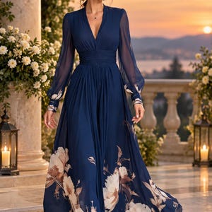 May include: A floor-length navy blue dress featuring a deep V-neckline, long sheer sleeves with buttoned cuffs, and a cinched waist. The skirt is made of a flowing fabric adorned with a large-scale cream and brown floral print at the hemline.