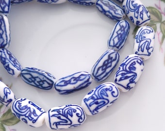 May include: A strand of white ceramic beads with blue and white floral designs. The beads are oval shaped and have a glossy finish.