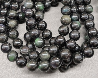 May include: A strand of black obsidian beads with iridescent rainbow shimmer. The beads are round and smooth, and they are strung on a clear thread.