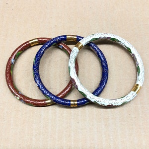 May include: Three enamel bangle bracelets with floral designs. One is red, one is blue, and one is white.