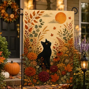 Könnte beinhalten: Eine rechteckige Gartenflagge mit einer schwarzen Katze, die inmitten einer herbstlichen Landschaft sitzt. Die Szene zeigt orangefarbene Chrysanthemen, dunkelrote Dahlien, fallende Ahornblätter, hohes Gras und eine große orangefarbene Sonne.