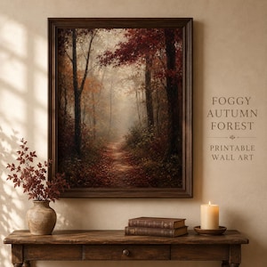 Può includere: Una stampa artistica da parete incorniciata che raffigura un sentiero nel bosco in autunno con fogliame rosso e arancione, alberi alti e scuri e nebbia fitta. Il testo FOGGY AUTUMN FOREST PRINTABLE WALL ART è stampato a destra della cornice.