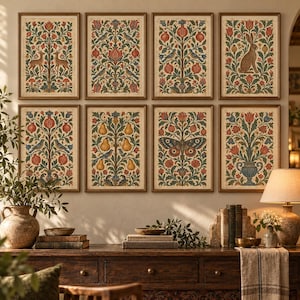 May include: A gallery wall featuring eight framed rectangular prints with botanical and animal illustrations in muted tones of red, green, and blue. The prints depict deer, birds, pomegranates, a rabbit, pears, a butterfly, and floral arrangements.