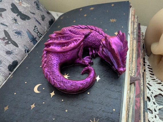 眠っているドラゴンの樹脂製の小さなフィギュア。光で明るい紫色の色が
