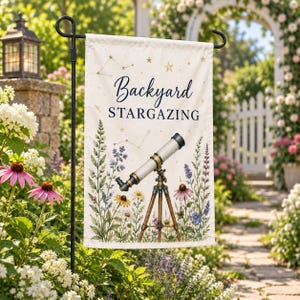 Op de afbeelding: Een rechthoekige tuinvlag met de tekst Backyard STARGAZING in donkerblauw, een centrale illustratie van een telescoop op een houten statief en omringende botanische elementen waaronder paarse, gele en witte wilde bloemen.