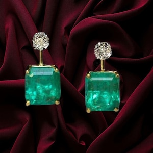 May include: A pair of earrings featuring a large, rectangular, faceted green gemstone suspended from a smaller, round, clear, faceted gemstone. The earrings are set in a metallic frame, showcasing a vibrant green hue and clear, sparkling accents.