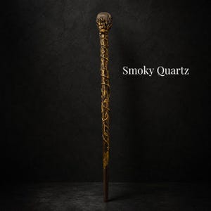 May include: A long, slender wand featuring a dark, textured shaft wrapped in gold-colored vine-like detailing. The top is crowned with a spherical smoky quartz gemstone held by metallic prongs. The text Smoky Quartz is visible to the right.