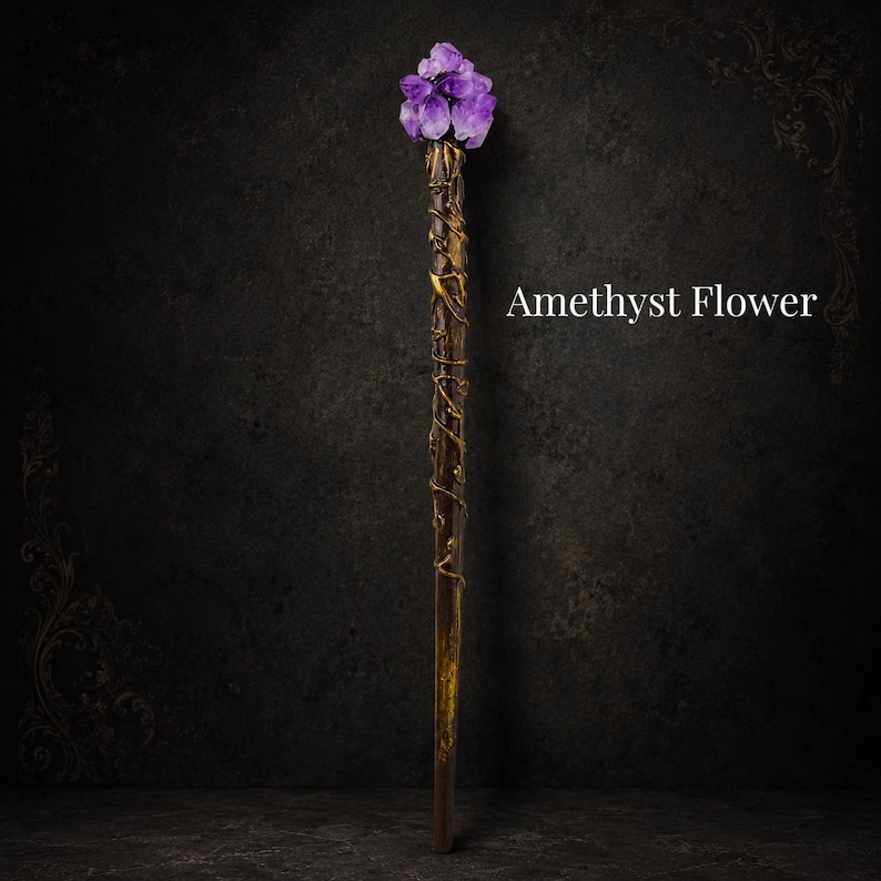 May include: A long, slender wand featuring a dark brown, textured handle wrapped in gold-colored vines. The top is adorned with a cluster of purple amethyst crystals arranged in a floral shape. The text Amethyst Flower is visible.