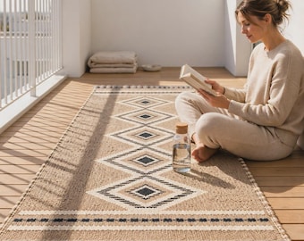 Op de afbeelding: Een rechthoekig geweven loper met een beige basis, een herhalend zwart-wit ruitpatroon, horizontale gestreepte randen en decoratieve franjes aan de korte zijden, geplaatst op een houten vloer.
