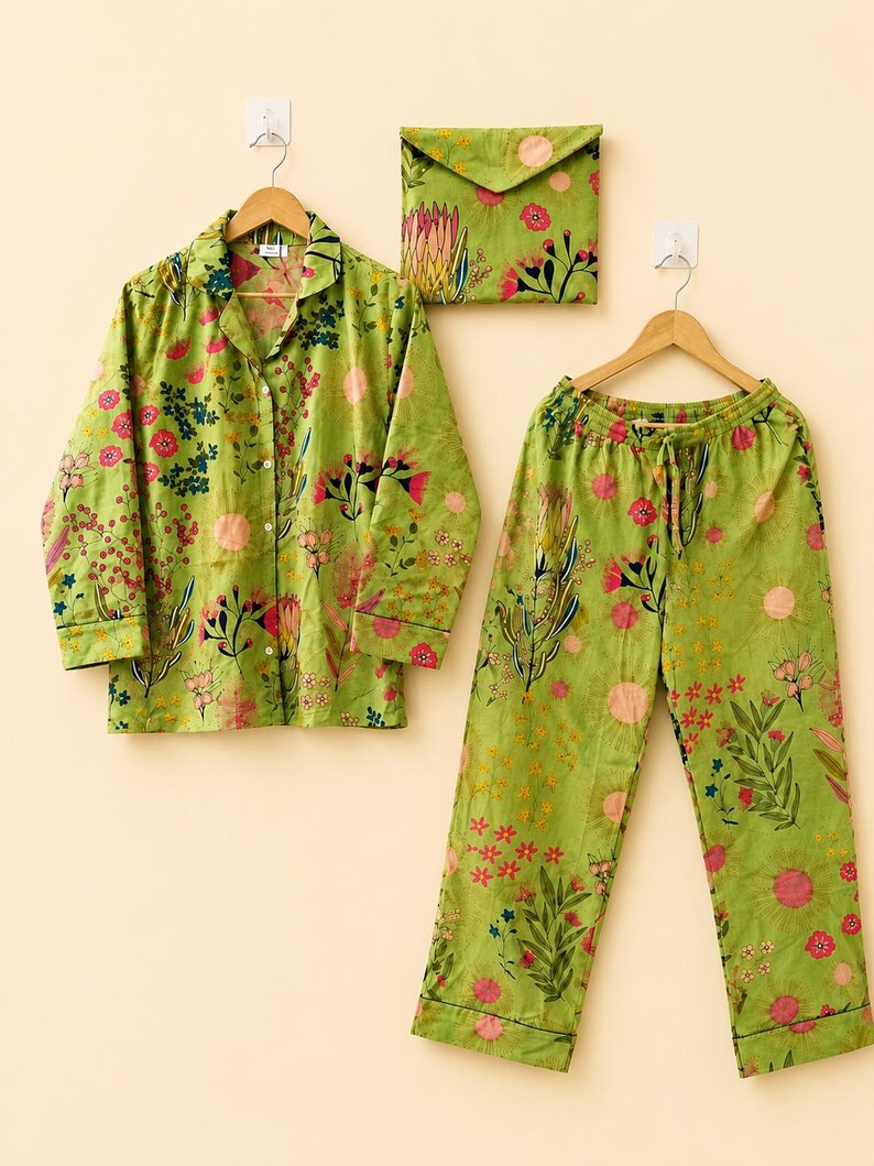 May include: A lime green pajama set featuring a long-sleeved button-down shirt and matching drawstring pants. The fabric is decorated with a colorful botanical print of pink, red, and yellow flowers, green leaves, and circular sun-like shapes.