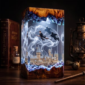 May include: A rectangular resin lamp featuring a wooden base and top with a clear center. Inside, a miniature castle sits at the bottom, while a figure on a broomstick and two dark cloaked figures float amidst swirling white smoke effects.