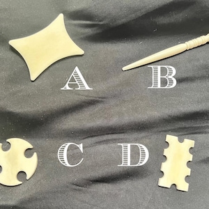 May include: Four small, off-white, antique objects are displayed on a black surface. The objects include a diamond-shaped piece, a long, pointed tool, a circular piece with four lobes, and a rectangular piece with notches. Letters A, B, C, and D are next to each object.