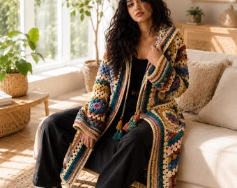 May include: A long-sleeved, open-front crochet cardigan featuring a multi-colored granny square pattern in shades of cream, blue, teal, yellow, and brown. The garment includes a hood, long sleeves, and decorative tassels hanging from the front neckline.