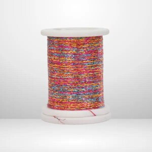 Op de afbeelding: Een klos metallic garen met een levendige, veelkleurige mix van roze, oranje, gouden en blauwe vezels. De draad is strak gewikkeld rond een witte cilindrische kunststof klos met platte, ronde uiteinden, wat zorgt voor een textuurrijk uiterlijk.
