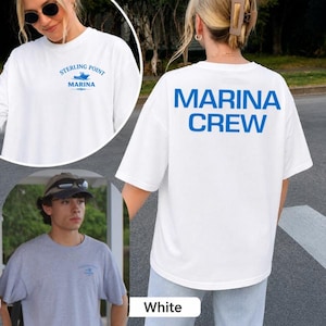 May include: A white short-sleeve t-shirt featuring the blue text MARINA CREW printed on the back. The front chest area displays a small blue graphic with the text STERLING POINT MARINA and a boat icon. The shirt is shown in a white colorway.