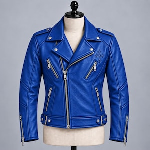 Puede incluir: Una chaqueta de moto de cuero azul vibrante con un emblema de cruz en relieve en el pecho, cremalleras de metal plateado, solapas con botones a presión, charreteras en los hombros y un cinturón ajustable con hebilla de metal.