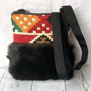 Pu&ograve; includere: Una piccola borsa a tracolla intrecciata colorata con un bordo in pelliccia sintetica nera e una tracolla nera regolabile.