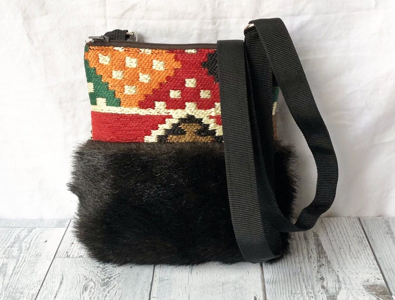 Pu&ograve; includere: Una piccola borsa a tracolla intrecciata colorata con un bordo in pelliccia sintetica nera e una tracolla nera regolabile.