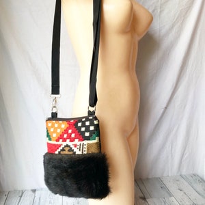 Pu&ograve; includere: Una piccola borsa a tracolla colorata con motivo geometrico e bordatura in pelliccia sintetica nera. La borsa ha una tracolla nera regolabile.