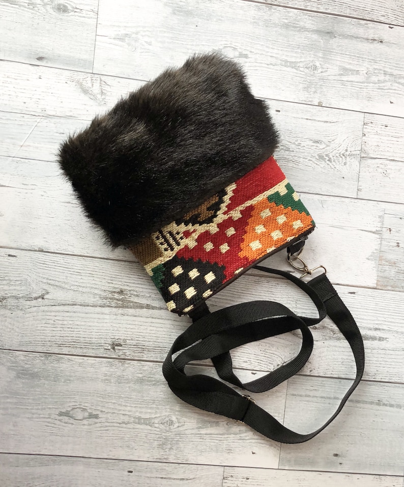 Pu&ograve; includere: Una piccola borsa colorata in tessuto con un bordo in pelliccia sintetica nera e una tracolla nera regolabile.