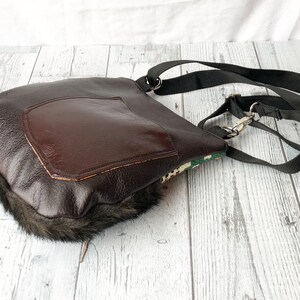 Pu&ograve; includere: Una borsa a tracolla in pelle marrone con un bordo in pelliccia sintetica. La borsa ha una grande tasca sul davanti e una tracolla nera regolabile.
