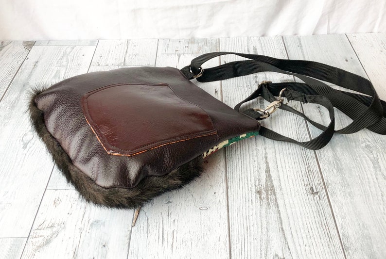 Pu&ograve; includere: Una borsa a tracolla in pelle marrone con un bordo in pelliccia sintetica. La borsa ha una grande tasca sul davanti e una tracolla nera regolabile.