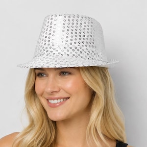 Puede incluir: Un sombrero fedora plateado cubierto de pequeñas lentejuelas circulares reflectantes. El sombrero presenta una copa estructurada y un ala corta inclinada hacia abajo. La superficie está compuesta totalmente por lentejuelas plateadas metálicas.