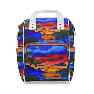 Puede incluir: Una mochila con una vibrante escena de atardecer que muestra siluetas de palmeras, montañas y un velero sobre el agua. El diseño incluye tonos azul profundo, naranja y rojo, complementado con asas superiores y bordes blancos en las cremalleras.