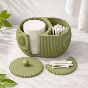 Puede incluir: Un organizador de baño de color verde oliva con textura acanalada y dos compartimentos. Un lado contiene una pila de discos de algodón blancos y el otro bastoncillos de algodón. Incluye dos tapas a juego, una circular y otra en forma de media luna.