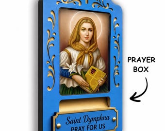 May include: A blue wooden wall-mounted prayer box featuring a central portrait of Saint Dymphna holding a book and lilies. The frame has a cutout cross at the top and a gold-toned plaque at the bottom with the text Saint Dymphna PRAY FOR US.
