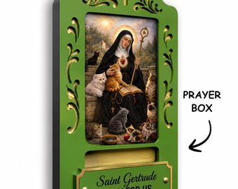 May include: A green wooden wall-mounted prayer box featuring a central image of Saint Gertrude surrounded by cats. The box includes a gold-toned plaque with the text Saint Gertrude PRAY FOR US and a cross cutout at the top with decorative scrollwork.