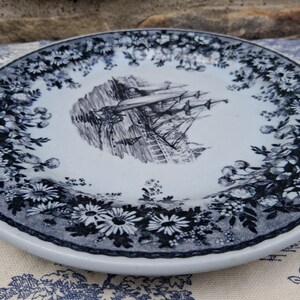 Pu&ograve; includere: Piatto in ceramica bianca con bordo floreale blu e bianco e un'illustrazione centrale di una nave. Il piatto ha un'estetica classica e vintage, adatto per servire cibo o come elemento decorativo.