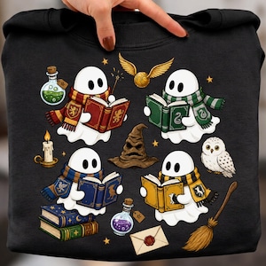 May include: A black sweatshirt featuring a graphic print of four white ghosts wearing colorful striped scarves and reading books. The design includes a brown sorting hat, a white owl, a broomstick, potion bottles, a candle, and a golden snitch.
