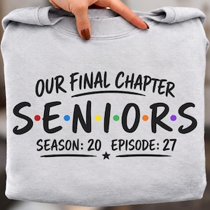 May include: A light gray crewneck sweatshirt featuring black text that reads OUR FINAL CHAPTER SENIORS SEASON: 20 EPISODE: 27. The word SENIORS includes colorful dots between the letters in red, blue, yellow, green, orange, and purple hues.