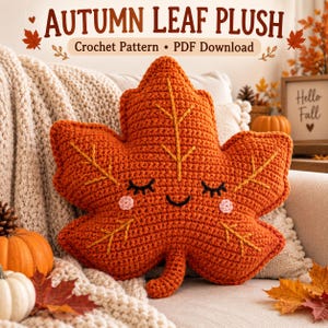 Pode incluir: Uma pelúcia de folha de crochê laranja com um rosto sorridente, olhos fechados e bochechas rosadas. A folha apresenta veios amarelos bordados. O texto no topo diz AUTUMN LEAF PLUSH Crochet Pattern PDF Download. A pelúcia tem formato de folha.