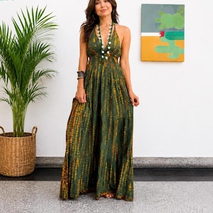 Puede incluir: Un vestido largo sin mangas en un tono verde oliva profundo con un patrón de teñido anudado vertical en tonos amarillo mostaza y marrón. La prenda tiene un escote en V profundo, un corpiño ajustado y una falda larga y fluida con dobladillo.