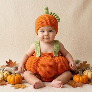 Può includere: Un completo a forma di zucca realizzato all'uncinetto, composto da una tutina arrotondata color arancione brillante con spalline verde chiaro e un berretto arancione abbinato con un piccolo stelo verde sulla sommità, lavorato a maglia spessa.